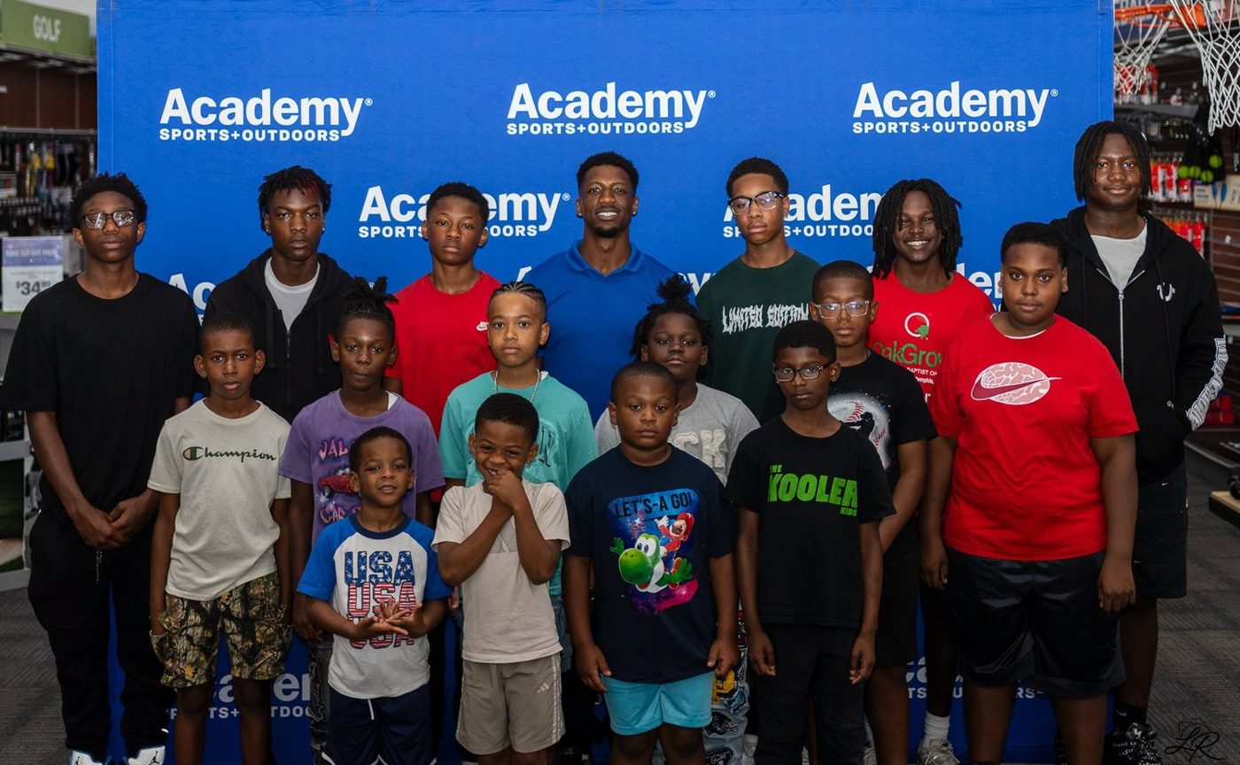 Large group of youth and families posing with Anthony Miller II at the Academy Sports backdrop