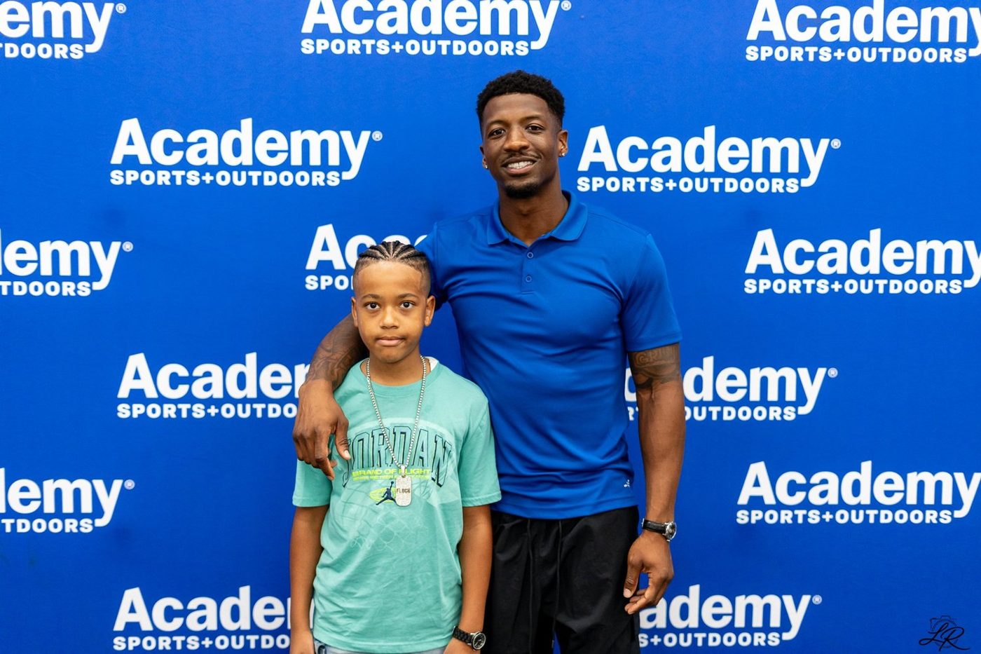 Anthony Miller II posing with a young camper at the Academy Sports backdrop