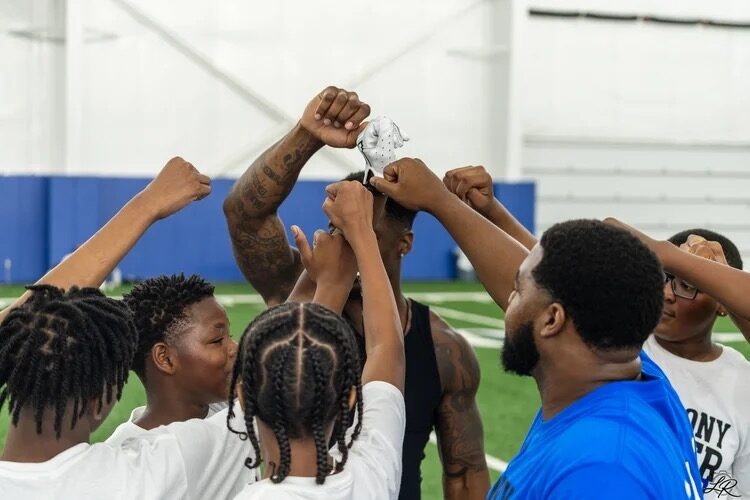 Campers and coaches in a team huddle with hands raised
