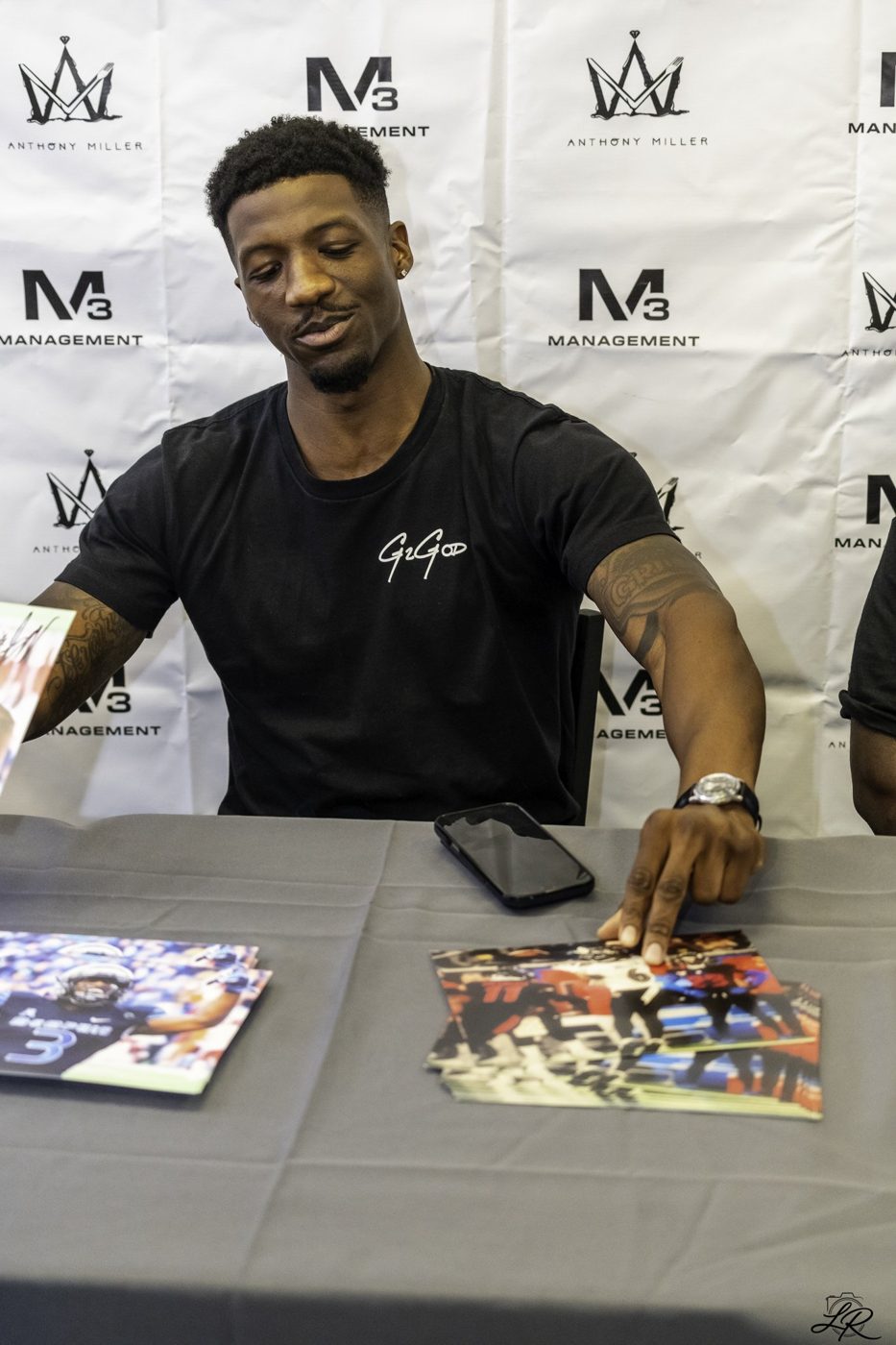 Anthony Miller signing autographed photos at the table